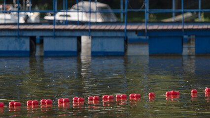 RELAXATION BY THE LAKE -  Marina in background and safety buoy line at swimming area on the foreground