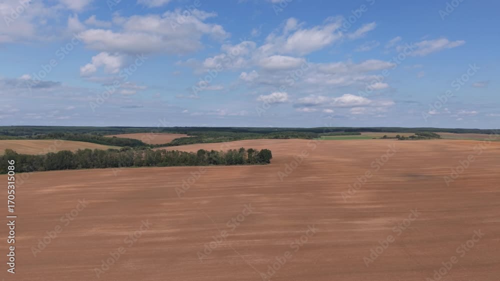 Poster an aerial view of wide open farmland with freshly plowed fields under a partly cloudy sky. the lands