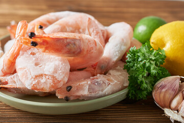 Frozen shrimps with lemon and parsley on a plate, close-up
