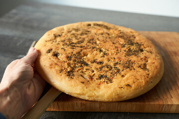 Focaccia with spices on a wooden board. Freshly baked.