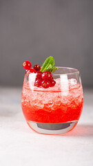 Vibrant red cocktail served in a clear glass filled with ice, topped with fresh mint and berries, perfect for summer gatherings, stories templates with copy space