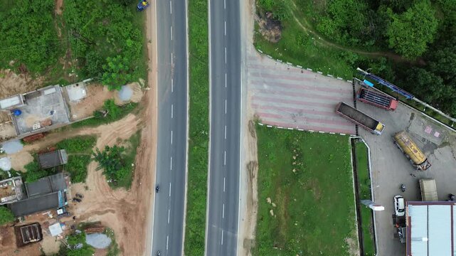 Aerial view of a road cutting through lush green vegetation, vehicles moving along the highway, contrasting the grey road with the green surroundings, Bundu, Jharkhand, India.