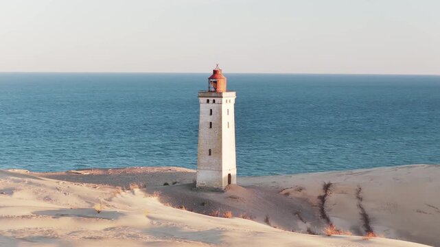Aerial view of Rubjerg Knude Lighthouse standing tall on shifting sands against the backdrop of the sea, Rujberg Knude, Denmark.