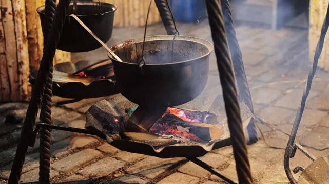 Soup is boiling in hanging cauldron over open flames at festive Riga Christmas