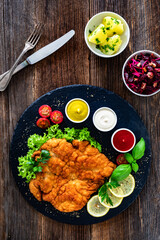 Garnished wiener schnitzel with ketchup, mayonnaise and mustard on wooden table
