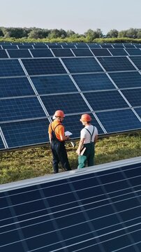 Engineers in hard hats inspect solar panels, promoting renewable energy and sustainability in a vertical video format.