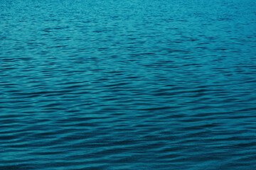 Close-up of calm sea water at dawn with subtle ripples. Deep blue tones with soft natural lighting. Peaceful and minimal aquatic texture for backgrounds or design.