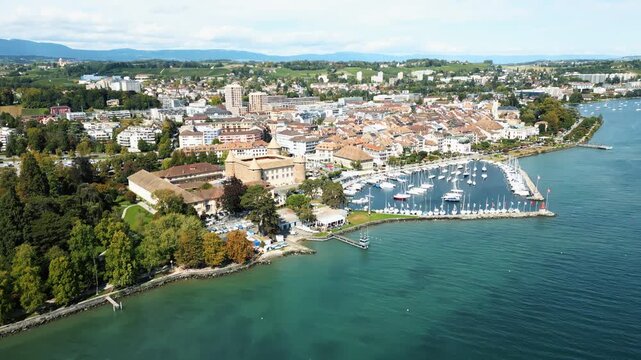 Aerial view of Morges featuring the historic Morges Castle near the marina and boats contrasting with the vibrant green trees, Morges, Vaud, Switzerland.