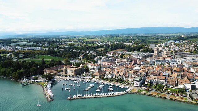 Aerial view of Morges Castle and the adjacent harbor, where the turquoise waters meet the buildings of Morges, Vaud, Switzerland.