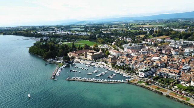 Aerial view of Morges Castle overlooking boats in the harbor, surrounded by the town's architecture and the expansive Lake Geneva, Morges, Vaud, Switzerland.