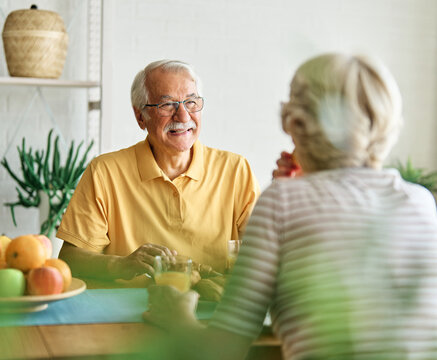 Portrait of an elderly senior couple having breakfast at home. Happy healthy affectionate senior couple eating and sitting at kitchen table having fun enjoying morning meal together