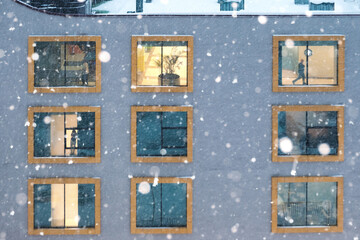 Illuminated windows of a building facade during snowfall