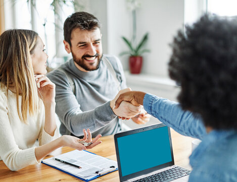 Portrait of a young couple shaking hands and closing a deal for aa new property purchase with real estate agent in her office