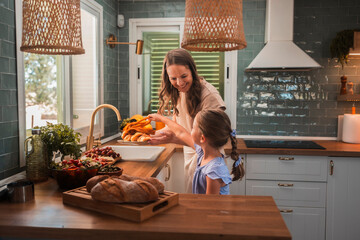 Mother giving croissants to daughter in modern kitchen