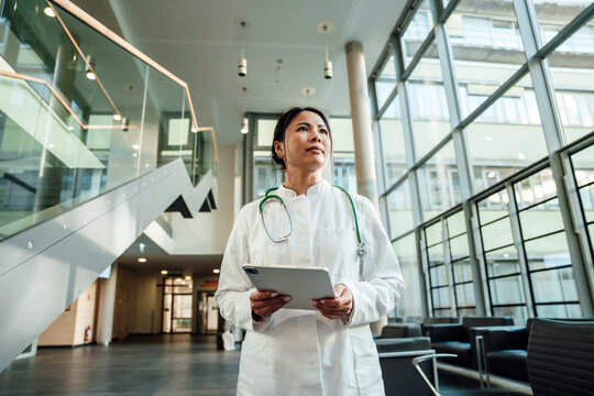 Doctor in modern clinic with tablet looking thoughtful and focused
