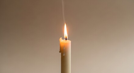 Lit candle with melting wax and rising smoke against a neutral beige background