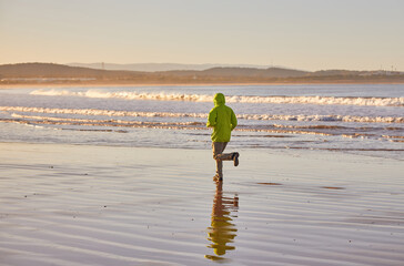 A young man in a green jacket enjoys a coastal run along Essaouira's ocean
