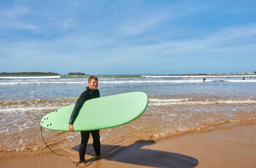 A young surfer strikes a pose with his board on the oceanfront in Essaouira