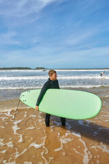 A young surfer strikes a pose with his board on the ocean's edge in Essaouira