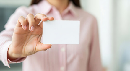 Professional businesswoman in a pink shirt presenting a blank white business card for mockup