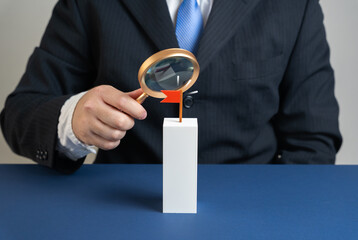 Businessman examines flag target with magnifying glass. Evaluation of target and resources to achieve it. Symbol of planning, performance, data analysis, and strategic decisions.