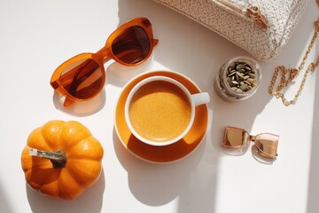 halloween coffee break, aesthetic flatlay with pumpkin latte, sunglasses, minimal fashion items, bright daylight