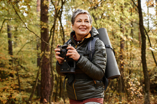 Joyful moments of a senior woman hiking through a vibrant autumn forest