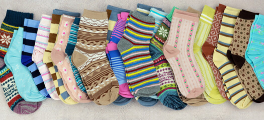 Many multi-colored socks are stacked in a row. Knitwear for cold seasons.