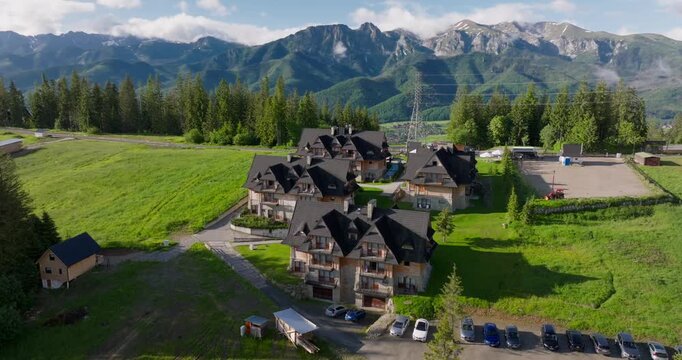 Aerial view of wooden mountain chalets on Gubał&oacute;wka Hill in Zakopane, Poland, with the scenic Tatra Mountains in the background, a popular spot for tourism.