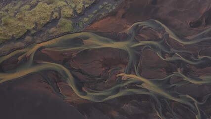 Aerial view of river delta creating a network of waterways across the landscape, with contrasting earthy tones from the land, Traustholtshólmi, Flóahreppur, Iceland.