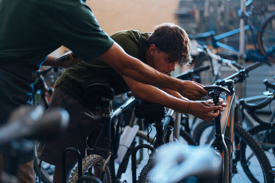 Bicycle mechanics repairing bicycles in workshop using digital tablet