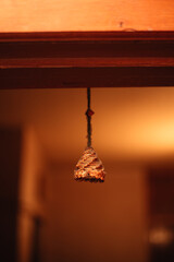 Three handcrafted straw bells hang from a wooden branch at an artisan market