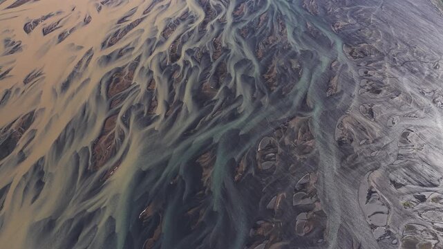Aerial view of a braided river with contrasting light and dark sediments creating an intricate network of waterways, Sk&uacute;mssta&eth;ir, Rang&aacute;r&thorn;ing eystra, Iceland.