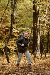 Fototapeta premium Senior woman enjoys hiking in a vibrant forest during autumn with a joyful spirit