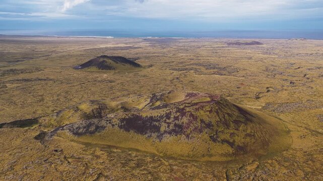 Aerial view of the rugged Saxh&oacute;ll Crater set against a backdrop of mossy lava fields and distant ocean views, Sn&aelig;fellsb&aelig;r, Iceland.
