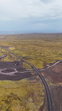 Aerial view of the stark contrast between the golden fields and dark volcanic earth surrounding Saxh&oacute;ll Crater, Hellissandur, Sn&aelig;fellsb&aelig;r, Iceland.