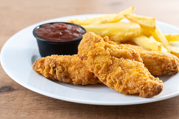 Crispy fried chicken tenders with french fries on wooden table