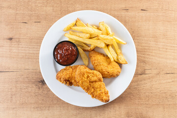 Crispy fried chicken tenders with french fries on wooden table