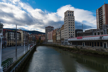 Naklejka premium View of the Bilbao river with a mix of historic and modern buildings.