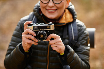 Senior woman capturing memories while hiking through a vibrant forest landscape
