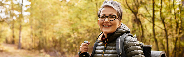 Senior woman enjoys a vibrant forest hike with joy and adventure during autumn
