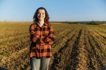 Young rural female farmer looking straight at camera in sunny farmland