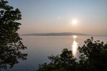 Sunset at the sea, an island in the background and trees in the foreground