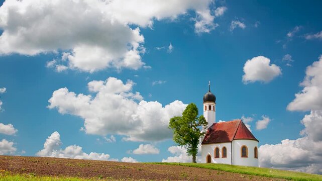 Zeitraffer von ziehenden Cumulus Sch&ouml;nwetterwolken hinter einer alleinstehenden romantischen Kapelle in Bayern