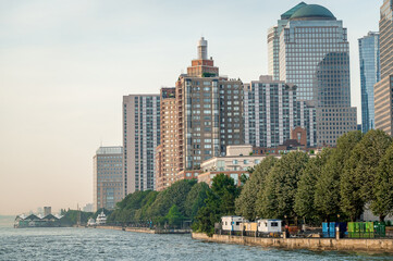 Obraz premium Buildings on the riverside in New York at sunset. Residential and office buildings in New York stand along the riverside under sunset light.