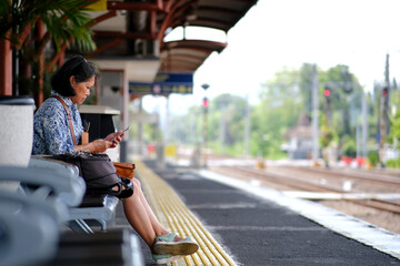 Asian commuter line passenger, sitting on a bench, waiting for her train to arrive