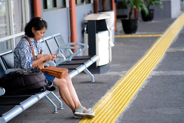 Asian commuter line passenger, sitting on a bench, waiting for her train to arrive