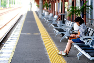 Asian commuter line passenger, sitting on a bench, waiting for her train to arrive