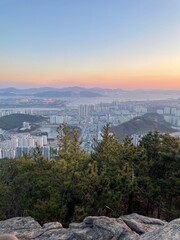 Obraz premium Cityscape with bridge and mountains at sunset.