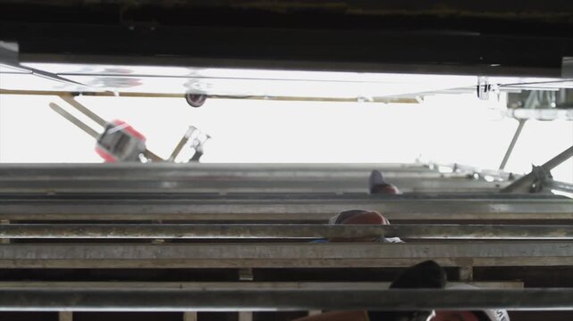 View from below of workers on scaffolding installing Corten steel panels onto a building fa&ccedil;ade.